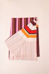 Pareo rectangular de viscosa con estampado de flores rojas sobre fondo borgoña y borde inferior con rayas verticales rojas, amarillas y blancas.