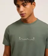 Remera verde militar de algodón, corte regular, cuello redondo, manga corta y estampa frontal con diseño de montañas y excursionistas en línea continua blanca.