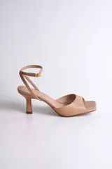 Sandalia de vestir color nude, con punta cuadrada, tira ancha sobre los dedos y pulsera al tobillo con hebilla dorada.