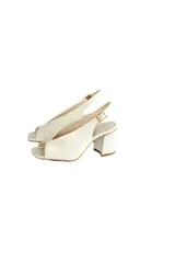 Zapato de cuero color blanco hueso, con taco cuadrado, punta abierta y tira trasera con hebilla.
