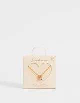 Cadena corta dorada con dije de tres aros dorados de los que cuelgan tres strass transparentes.