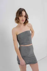 Minifalda negra ajustada al cuerpo, confeccionada en tejido elástico con strass plateado.
