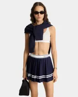Minifalda de tenis tableada color azul marino con cintura elástica blanca con logo bordado. Tiene dos líneas horizontales blancas en el ruedo y short interior.
