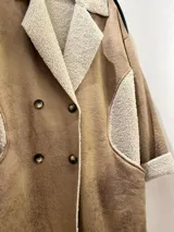 Tapado largo color beige, con interior y exterior de gamuza sintética y detalles de corderito sintético en cuello, bolsillos y puños. Cierre frontal con doble botonadura.