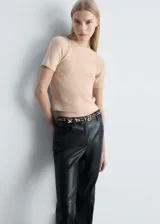 Buzo de punto medio color beige, con cuello redondo y mangas cortas. Diseño recto.