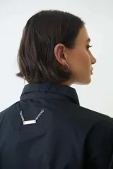 Camisa corta negra de corte holgado, abotonada al frente y con cuello camisero.