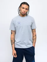 Remera color crema de corte clásico con cuello redondo y estampado en la espalda de una huella digital con forma de pelota de fútbol y el logo de Umbro.