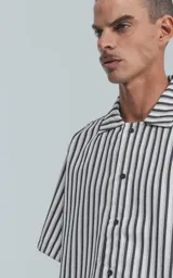 Camisa de manga corta con cuello abierto y corte oversize, a rayas verticales blancas y negras.