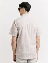 Camisa de manga corta con cuello abotonado y estampado a rayas verticales color beige y blanco.