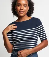 Blusa de punto con textura acanalada, escote barco y manga corta. Presenta un estampado de rayas horizontales en color blanco sobre fondo azul marino.