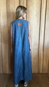 Vestido largo color crudo, sin mangas y con escote en V. Presenta aberturas laterales en el ruedo y bolsillos laterales a la altura de la cadera.