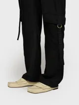 Enterito negro de piqué y sarga de Tencel lavado, con escote en V, mangas largas y corte holgado. Presenta bolsillos de parche en pecho y espalda, bolsillos laterales y cinturón doble de cordón. Tiene detalles de bordado en el pecho y un parche con borde sin rematar en la espalda.