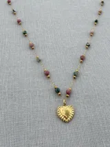 Collar con cadena de acero dorado, intercalando cuentas de piedra natural de rodocrosita (rosada) y turquesa africana (verde), con un dije central en forma de corazón dorado.