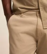 Pantalón de vestir color marrón, de corte recto, con bolsillos laterales y traseros. Se ajusta a la cintura con cinturón de cuero marrón.