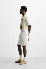 Bermuda relaxed fit color blanco confeccionada en tejido interlock de algodón con elasticidad. Cintura elástica ajustable con cordón interior. Bolsillos laterales y detalle de bolsillo trasero de plastrón.