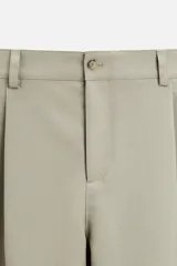 Pantalón negro de corte amplio tipo balloon fit, con cintura con pliegues frontales, bolsillos delanteros y traseros de plastrón. Cierre frontal con cremallera y botón.