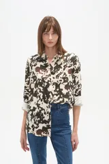 Camisa de viscosa con estampado que simula manchas de vaca en tonos blanco, negro y marrón. Presenta un corte holgado, cuello camisa y mangas largas con puños.