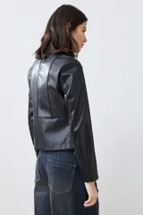 Chaqueta corta de cuero sintético color negro, con cuello redondo y cierre frontal. Presenta detalle de pasamanería en hombros y cuello.