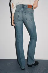 Pantalón de jean azul oscuro, de tiro bajo, corte slim fit y bootcut. Con cinco bolsillos y cierre frontal con cremallera y botón.