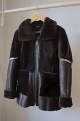 Campera gamulán marrón con cierre frontal, cuello solapa y bolsillos laterales.