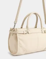 Cartera tipo bowling color crema, de cuerina, con doble asa corta de mano, tira envolvente con hebilla y correa regulable y desmontable.