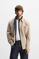 Sobrecamisa negra de tejido con elasticidad, cuello solapa y manga larga acabada en puño con botón a presión. Tiene bolsillos de plastrón en el pecho y cierre frontal con botones a presión.