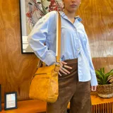 Bandolera color beige con correa larga regulable combinada a tono. Tiene dos bolsillos frontales con cierre, apertura superior con cierre, división interna, bolsillos internos y bolsillo trasero con cierre.