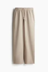 Pantalón deportivo color beige de corte holgado, confeccionado en felpa de algodón liviano con efecto lavado. Cuenta con cintura elástica fruncida, cordón para ajustar, bolsillos laterales discretos y bajos sin rematar.