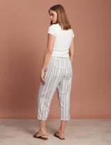 Pantalón capri de lino color blanco con rayas verticales azules y marrones, con cintura elástica ajustable con cordón.