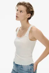 Musculosa blanca de punto pointelle suave, corte ajustado, con escote cuadrado, moño de satén y bajo sobrehilado.