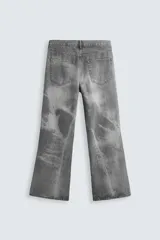 Pantalón de jean gris de corte flare, con cinco bolsillos, lavado con efecto de contraste en las piernas y bajo con acabado irregular.