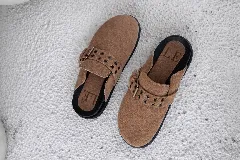 Zuecos cerrados de cuero marrón oscuro, con puntera redonda y tira ancha con hebilla metálica y ojales.