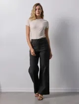Pantalón de jean blanco de pierna ancha, tiro alto, pretina con pasadores, botón y cierre. Delantera y trasera con bolsillos.