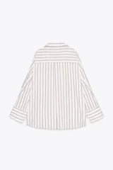 Camisa blanca con rayas verticales grises, de corte holgado, cuello solapa y mangas largas con puños abotonados. Tiene un bolsillo de parche en el pecho, pinzas en la espalda y bajo asimétrico con aberturas laterales.