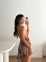 Vestido corto con estampado abstracto en tonos marrones, escote halter pronunciado, espalda descubierta, detalle de estrella de mar dorada en la cintura y falda irregular con volados.