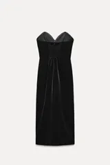 Vestido midi negro de terciopelo, palabra de honor con escote corazón y hombros descubiertos. Tiene detalle de elástico tipo nido de abeja en la espalda y abertura en el bajo.