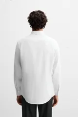 Camisa de vestir verde oscuro, corte slim fit, con cuello italiano, mangas largas con puños abotonados y cierre frontal con botones.