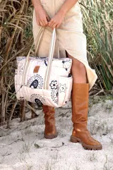 Bolso tipo tote, capitoneado a mano, con estampado de flores y paisley en blanco y negro. Tiene tres bolsillos interiores y cinco exteriores.