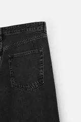 Pantalón de jean negro de corte amplio, con cinco bolsillos, efecto lavado y cierre frontal con cremallera y botón.