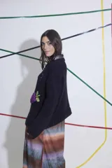 Sweater tejido a mano en lana merino color naranja, con bordado de texto en azul y apliques de uvas en azul. De calce holgado, cuello redondo y puños ajustados.