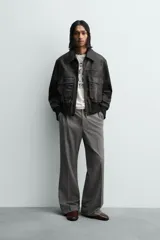 Cazadora estilo bomber cropped fit de piel negra, con cuello solapa, cierre frontal de cremallera, bolsillos frontales de plastrón con solapa y puños y bajo de rib elástico ancho.