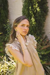 Blusa de lino color blanco, sin mangas, con cuello fruncido y volados de encaje en las sisas. Presenta pinzas frontales y un diseño de calce holgado de estilo romántico.