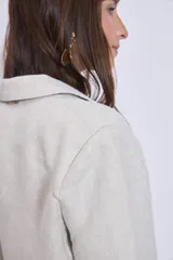 Blazer color crema de lino con corte clásico, solapas de muesca y cierre cruzado con un botón. Incluye un pañuelo de seda estampado atado a la cintura.