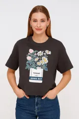 Remera gris oscuro con estampado de flores y texto en la parte delantera.