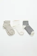 Pack de tres pares de medias de caña media con diseño acanalado. Un par es color gris claro liso, otro es blanco con pequeños lunares y el tercero es blanco con rayas horizontales negras.