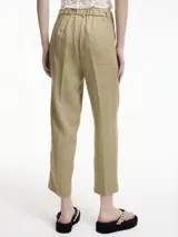 Pantalón de lino color beige, corte recto y tiro medio, con pliegues frontales y bolsillos laterales.