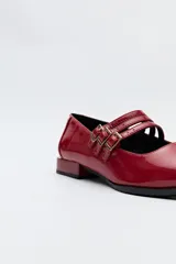 Zapato tipo Mary Jane color negro con textura de reptil, de charol sintético con punta cuadrada y triple tira con hebillas.