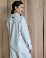 Camisa de denim color beige, con detalles de volados sutiles y frunces en los hombros.
