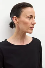 Remera negra de manga tres cuartos con escote bote y un lazo o bufanda del mismo material anudado al cuello.