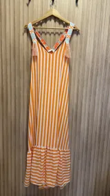 Vestido largo de algodón con rayas verticales naranjas y blancas. Breteles con detalle de bordado floral y flecos.